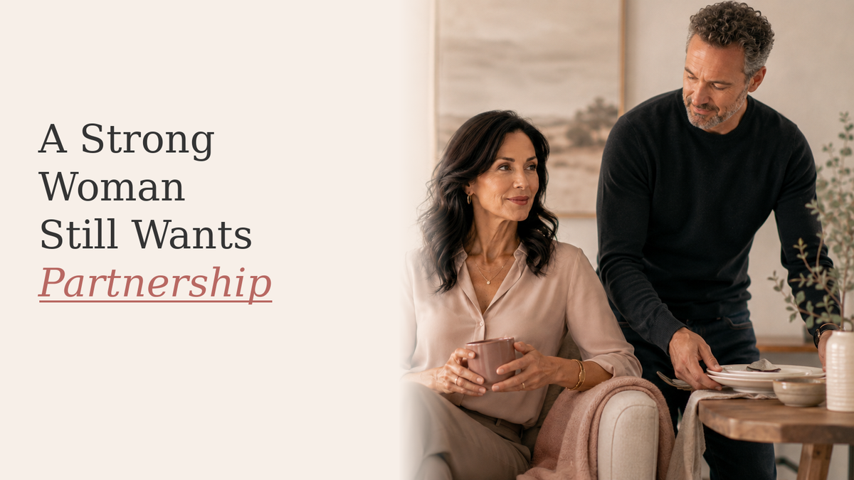 Strong midlife woman relaxing on a sofa with a supportive partner close beside her in a warm neutral home.